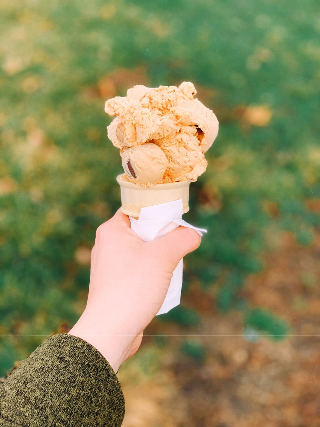 ice cream cone being held with grass in the background